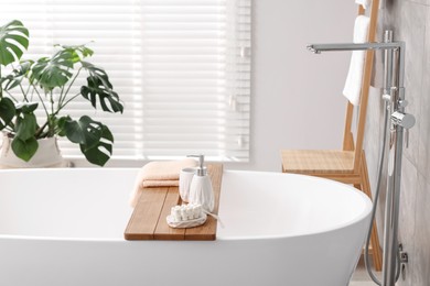 Photo of Set of different bath accessories and soap on tub in bathroom