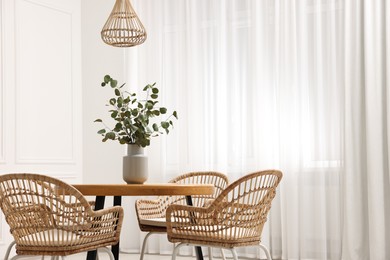 Photo of Dining room interior with comfortable furniture and eucalyptus branches. Space for text