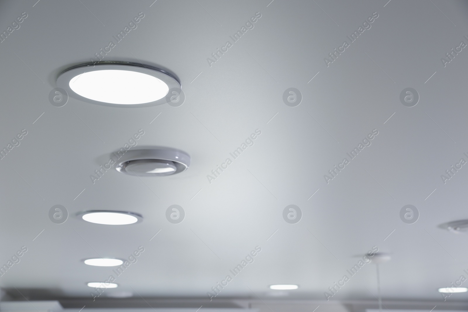 Photo of White ceiling with lamps indoors, below view