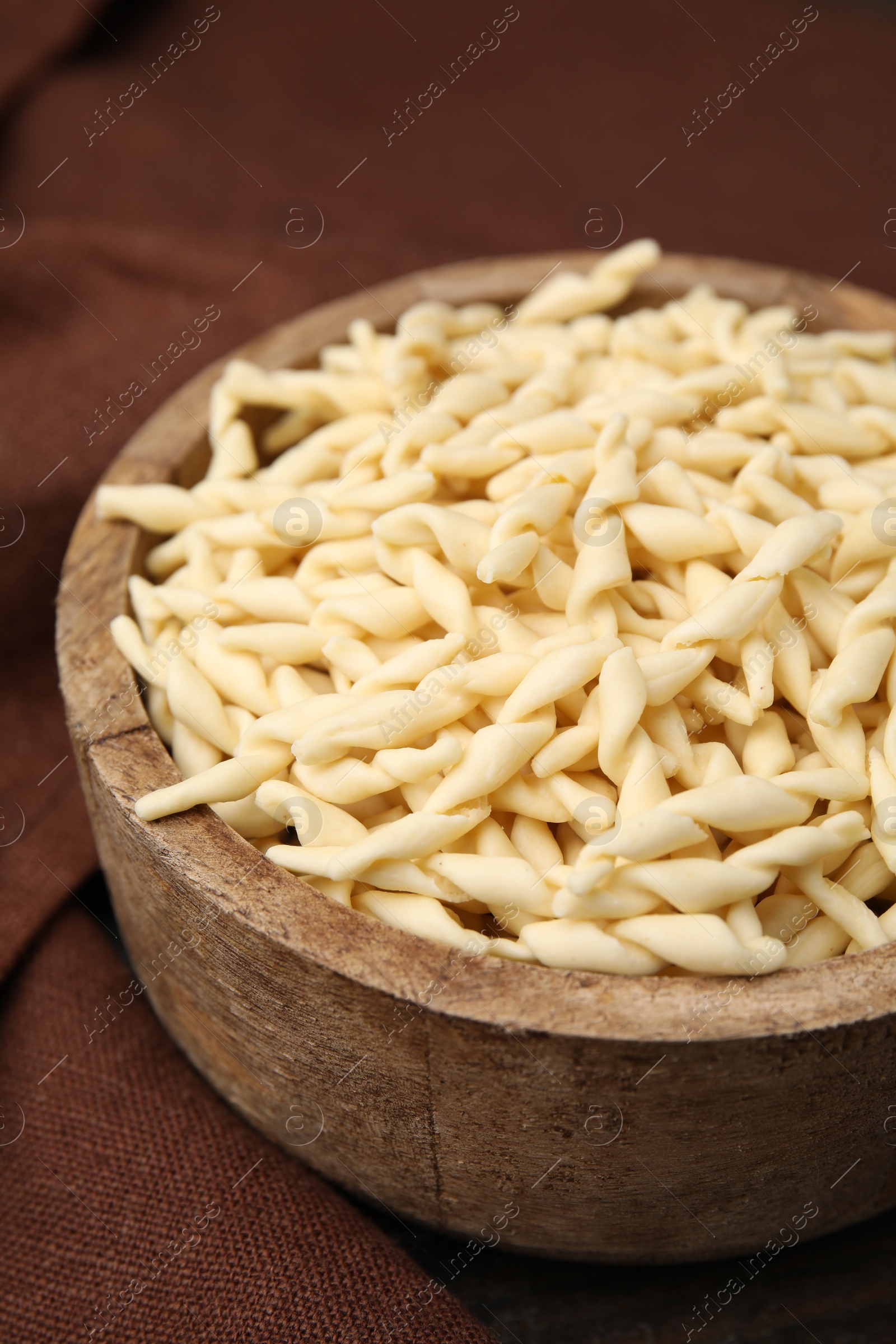 Photo of Uncooked trofie pasta in bowl on table, closeup