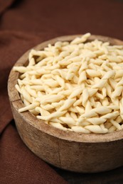 Photo of Uncooked trofie pasta in bowl on table, closeup