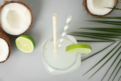 Mason jar with coconut water and fresh nuts on grey background, top view