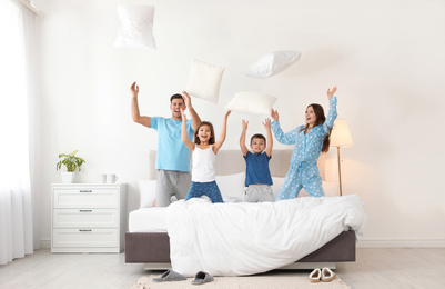 Photo of Happy family playing with pillows in bedroom