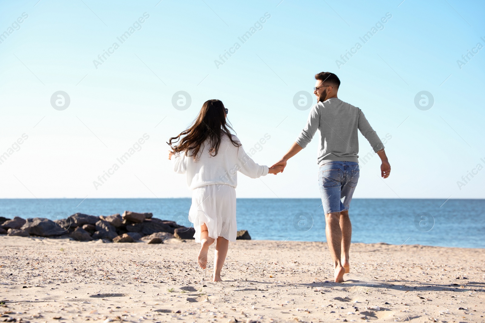 Photo of Happy young couple on beach near sea. Honeymoon trip