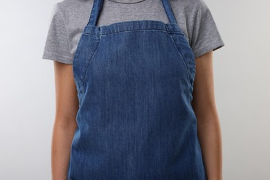 Photo of Woman wearing kitchen apron on light grey background, closeup. Mockup for design