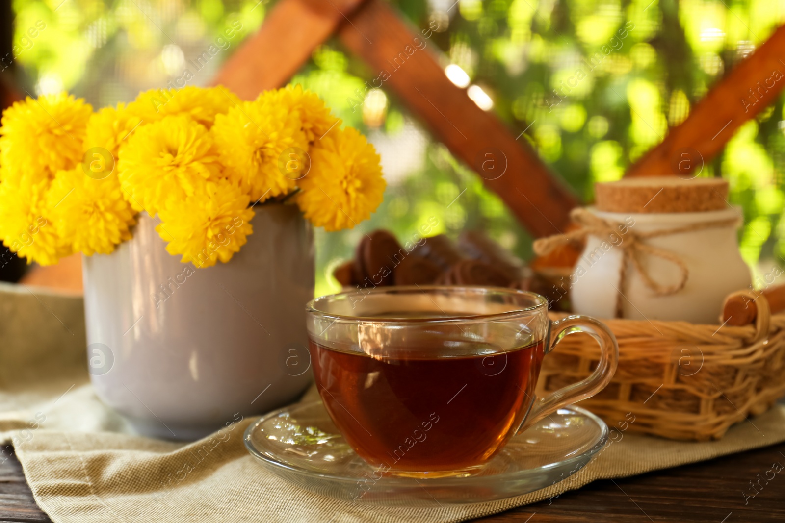 Photo of Beautiful yellow chrysanthemum flowers and cup of aromatic tea on wooden table