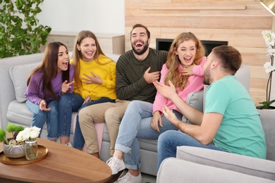 Photo of Group of friends telling jokes and laughing in living room