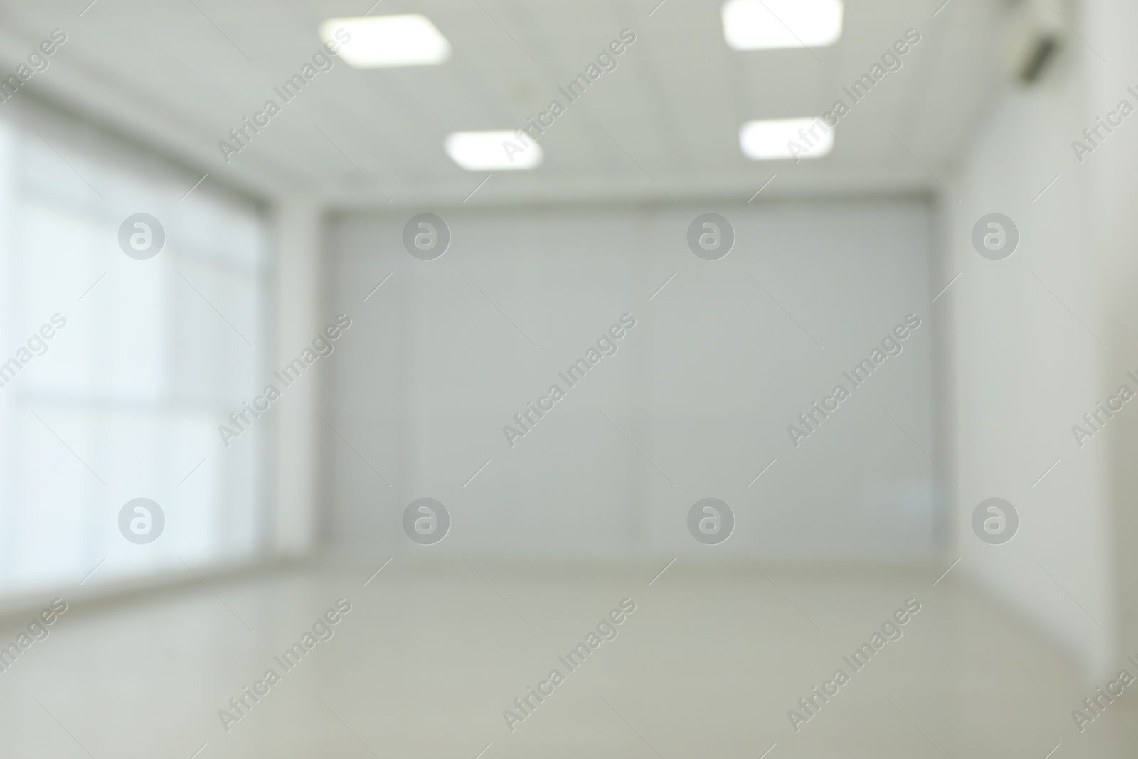 Photo of Empty room with white wall and laminated flooring, blurred view