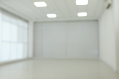 Photo of Empty room with white wall and laminated flooring, blurred view