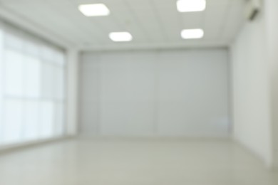 Empty room with white wall and laminated flooring, blurred view