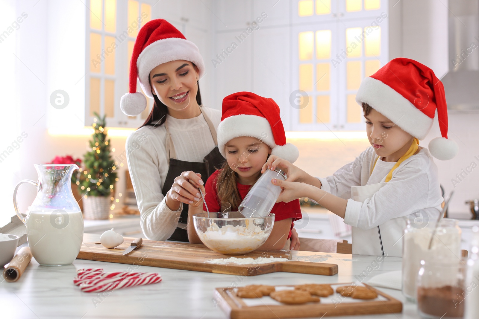 Photo of Mother with her cute little children making Christmas cookies in kitchen