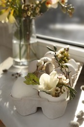 Festive composition with eggs and floral decor on windowsill indoors. Happy Easter