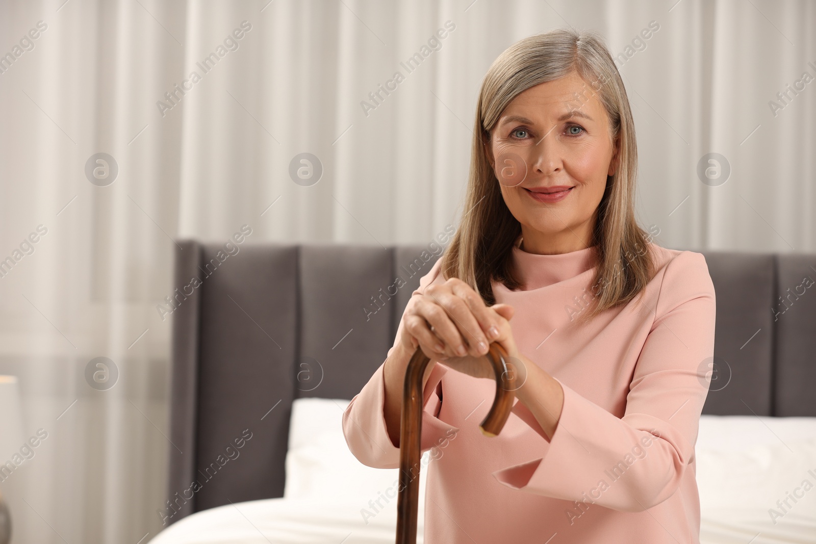 Photo of Mature woman with walking cane on bed at home