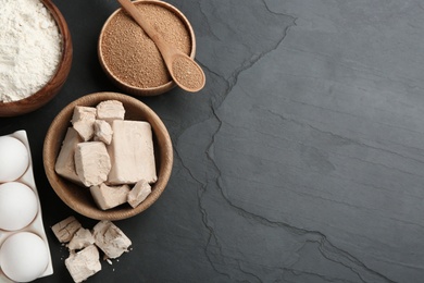 Yeast and dough ingredients on black table, flat lay. Space for text