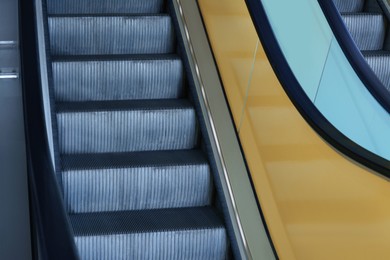 Photo of View on empty parallel escalators with yellow balustrades, closeup