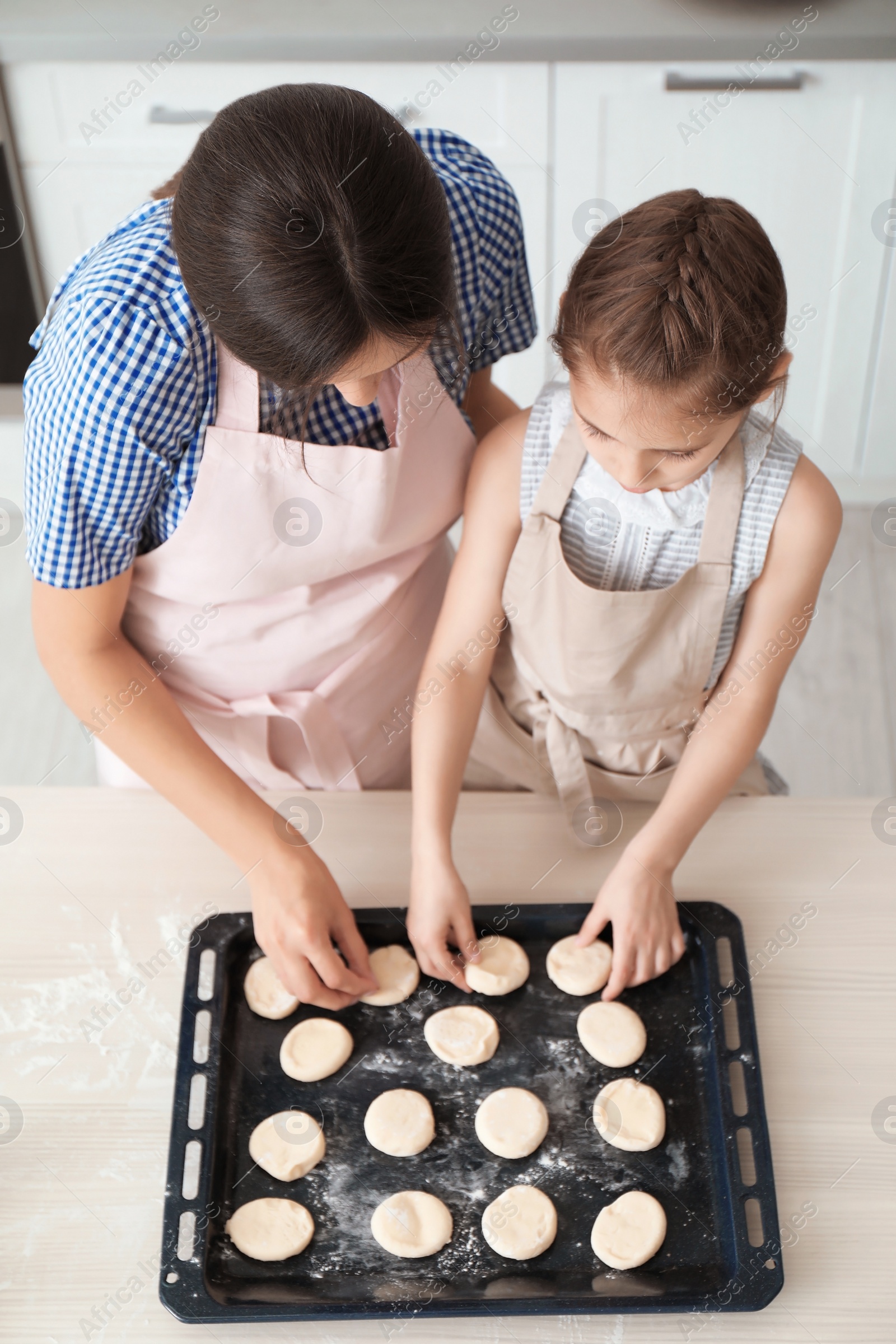 Photo of Mother and her daughter with cookie dough in kitchen