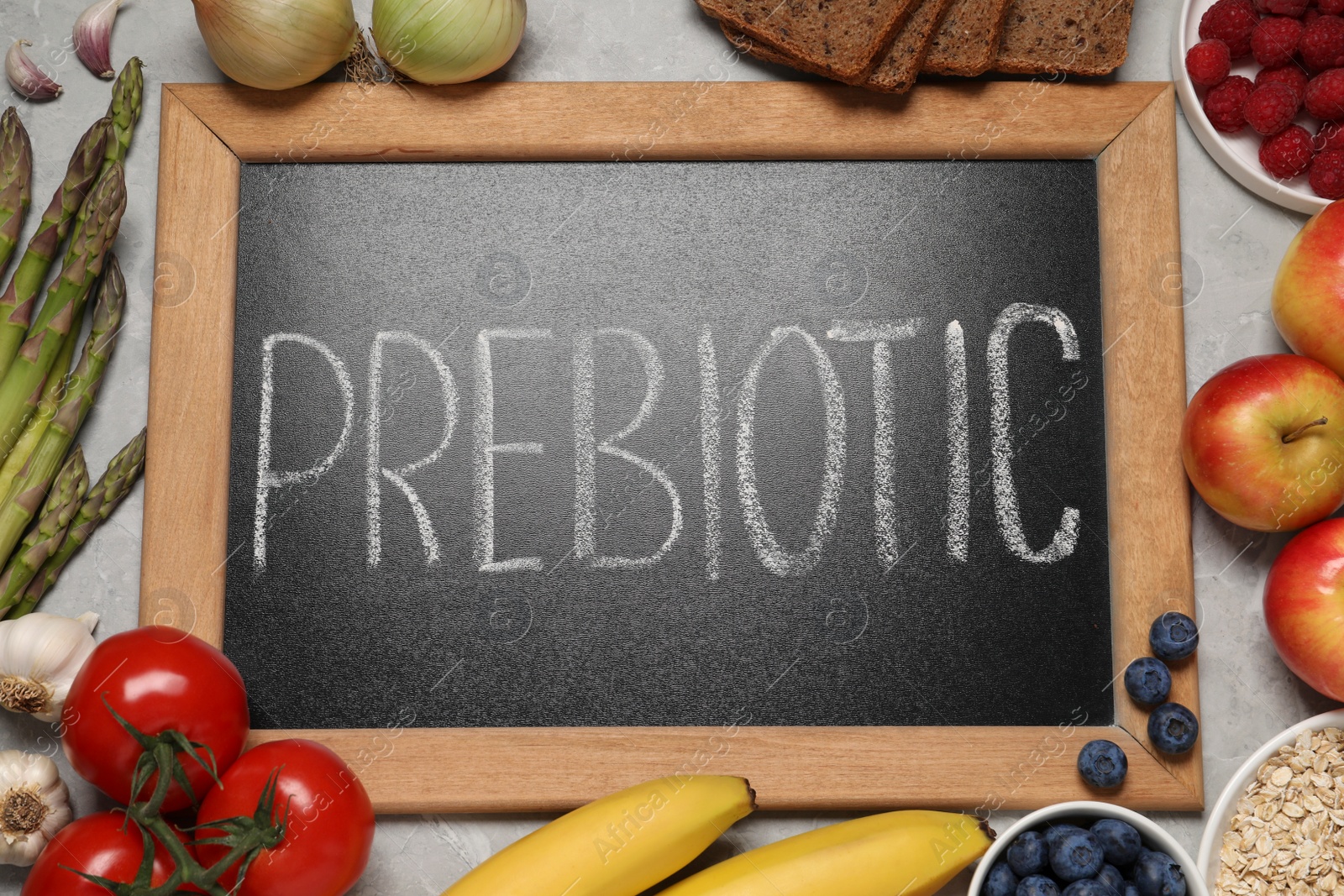 Photo of Blackboard with word Prebiotic and different products on grey table, flat lay