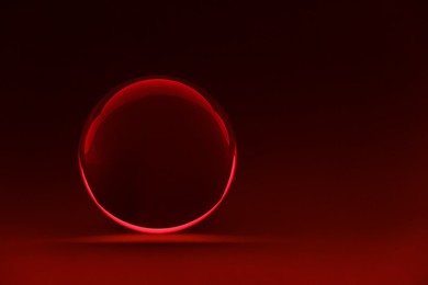 Photo of Transparent glass ball on dark red background. Space for text
