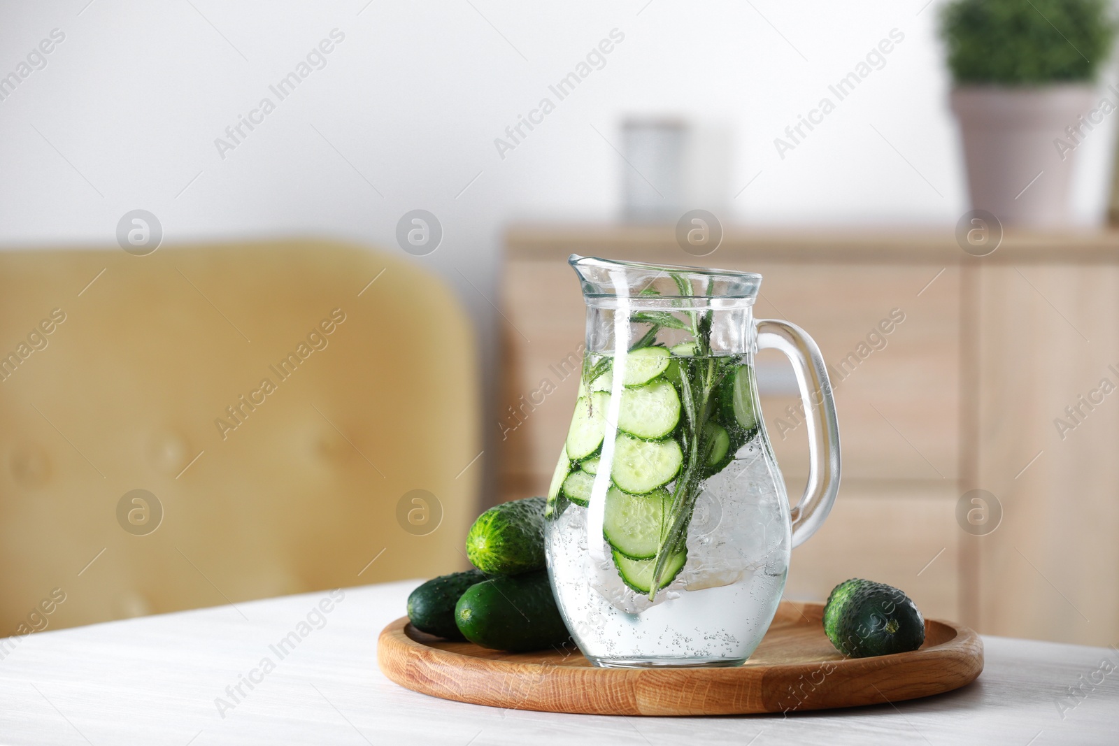 Photo of Refreshing cucumber water with rosemary in jug and vegetables on white table. Space for text