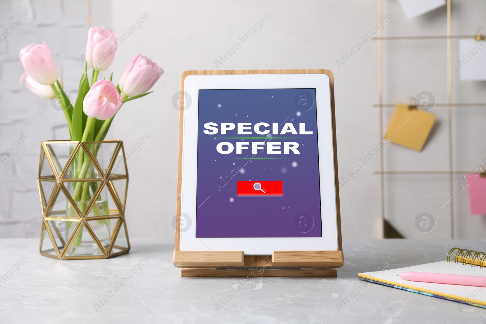 Image of Modern tablet with phrase Special Offer, stationery and flowers on grey marble table