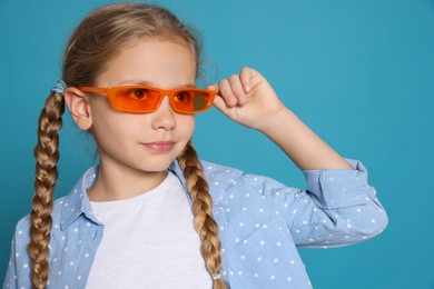 Photo of Girl in orange sunglasses on light blue background