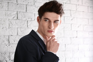 Portrait of young businessman with beautiful hair on brick wall background