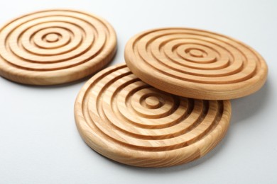 Stylish wooden cup coasters on light background