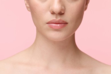 Woman wearing beautiful lip gloss on pink background, closeup