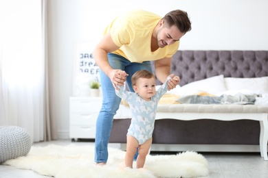 Baby taking first steps with father's help at home