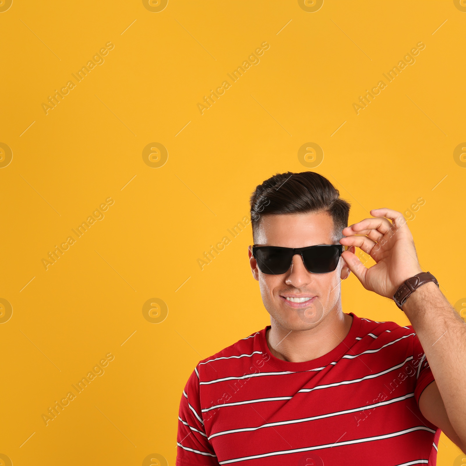 Photo of Handsome man wearing sunglasses on yellow background. Space for text