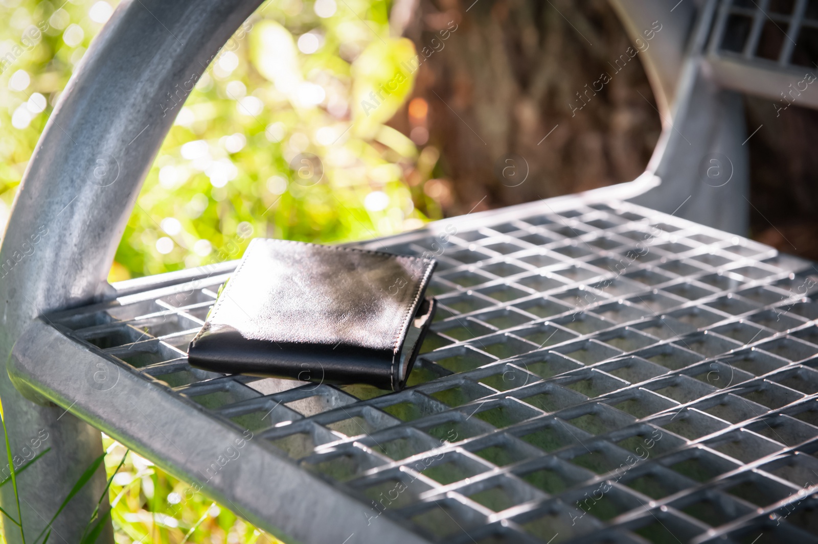 Photo of Black wallet on metal bench outdoors. Lost and found