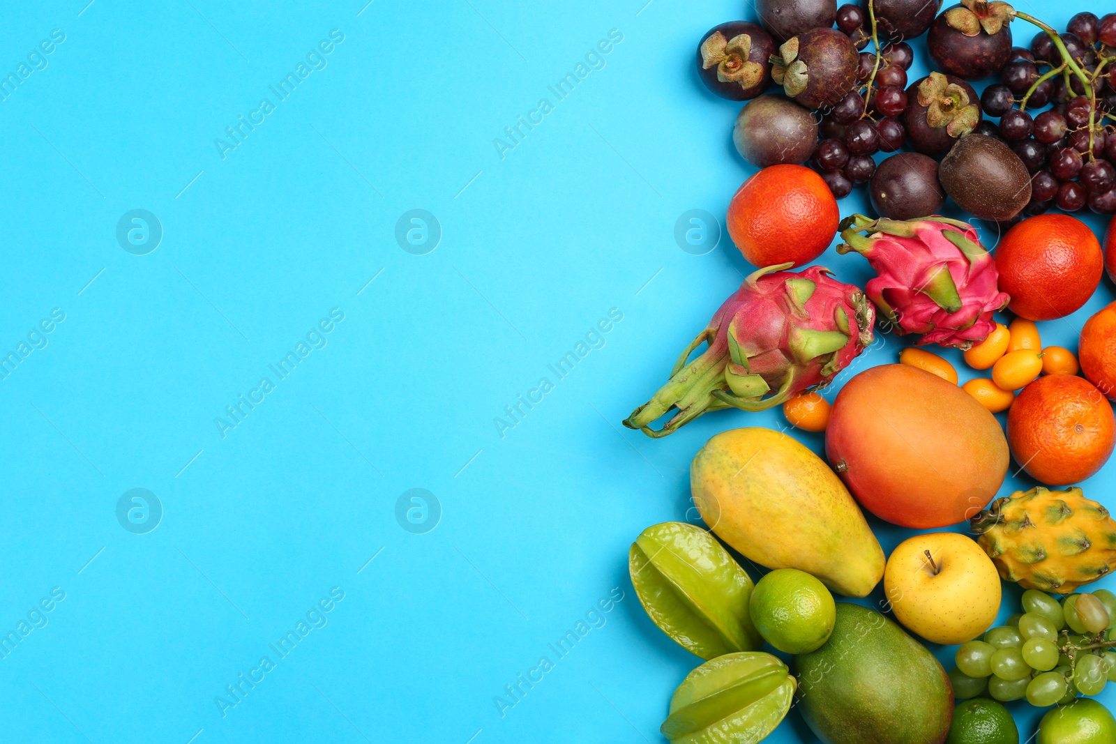 Photo of Assortment of fresh exotic fruits on light blue background, flat lay. Space for text