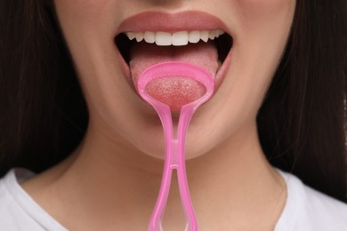 Photo of Woman brushing her tongue with cleaner, closeup
