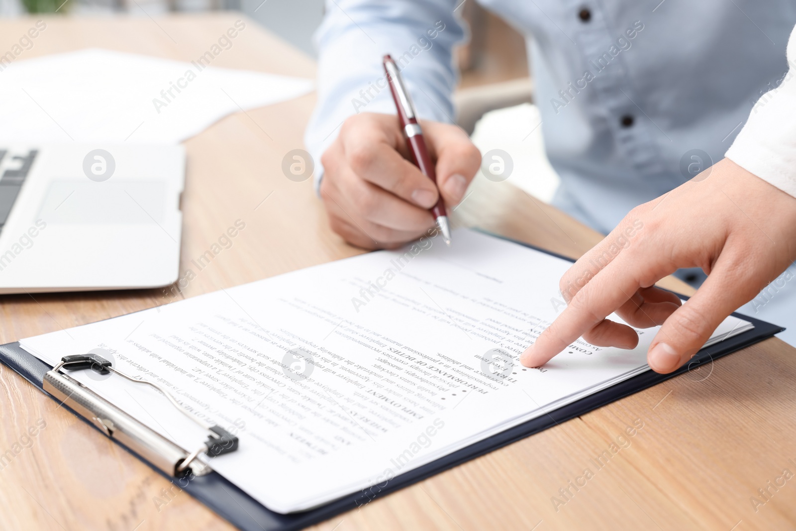 Photo of Businesspeople signing contract at wooden table, closeup