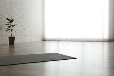 Photo of Unrolled grey yoga mat on floor in room. Space for text