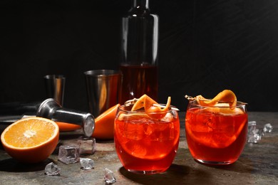 Photo of Aperol spritz cocktail, ice cubes and orange slices in glasses on grey textured table