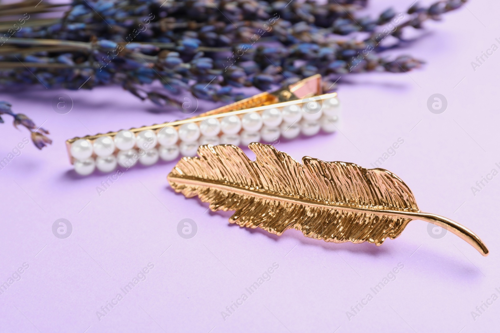 Photo of Stylish hair clips and flowers on violet background