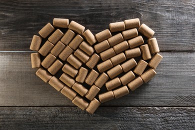 Heart made of wine bottle corks on wooden table, top view