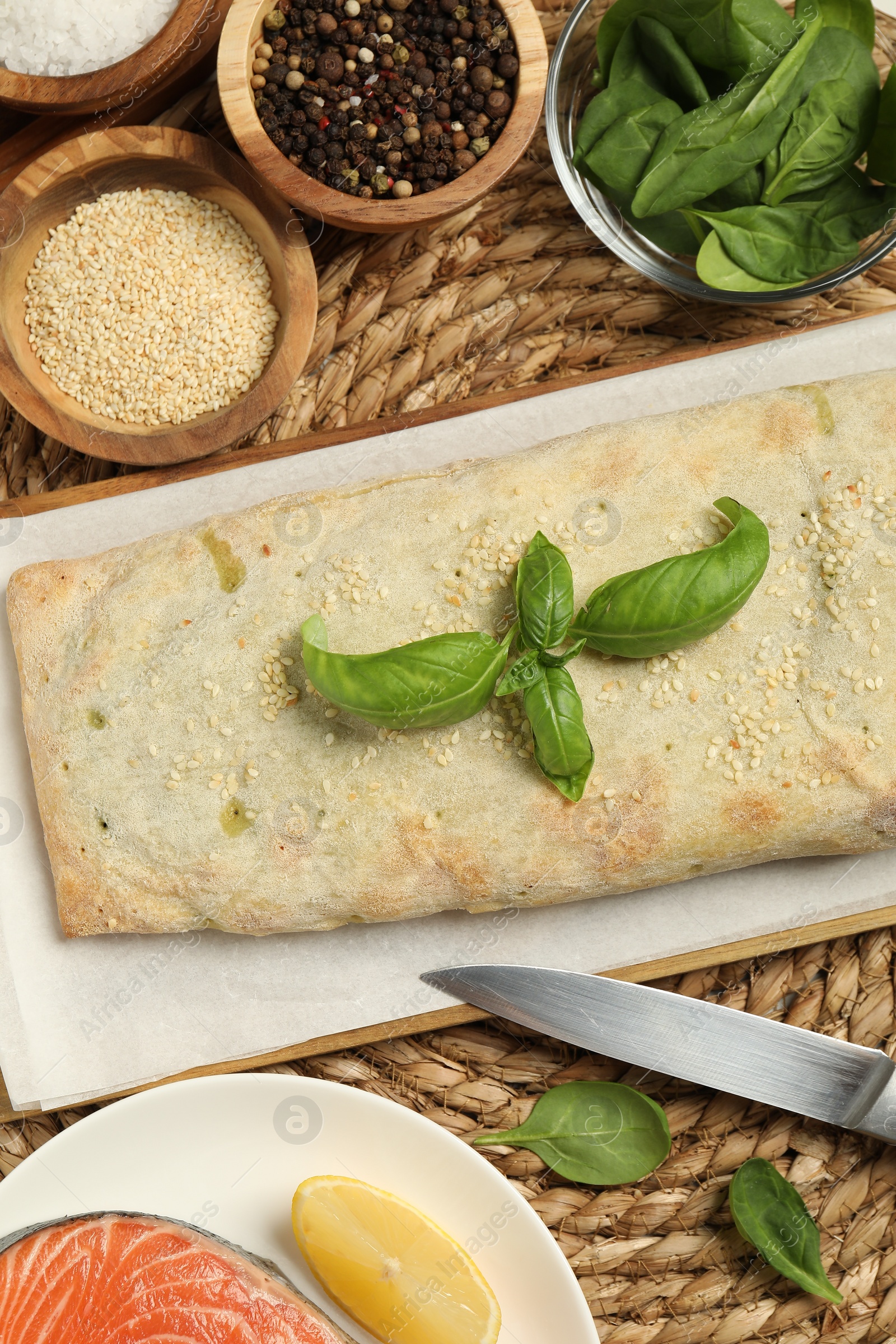 Photo of Delicious strudel with tasty filling and basil served on wicker mat, flat lay