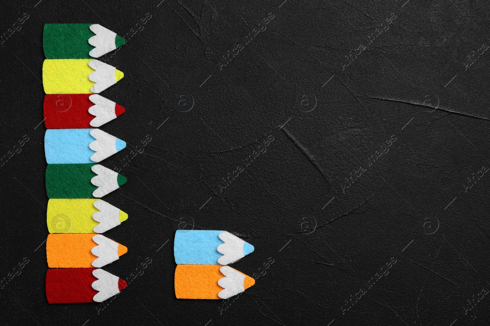 Photo of Flat lay composition with colorful felt pencils on black stone background, space for text. Pareto principle concept