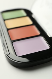 Photo of Colorful correcting concealer palette on white background, closeup