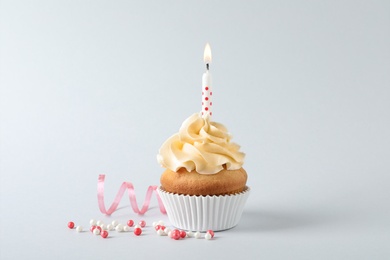 Photo of Delicious birthday cupcake with candle on gray background