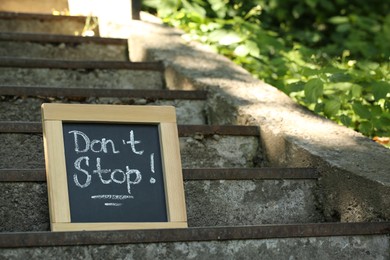 Photo of Chalkboard with phrase Don't Stop on stone stairs outdoors, space for text