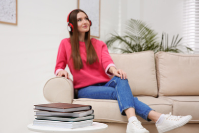 Photo of Woman listening to audiobook on sofa at home, focus on books
