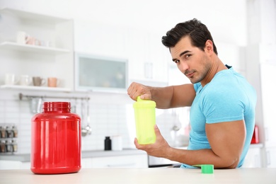 Photo of Young athletic man preparing protein shake in kitchen