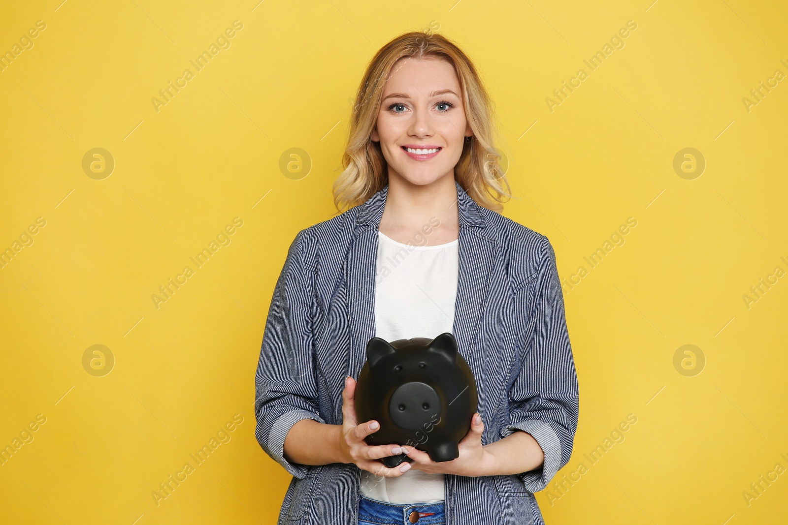 Photo of Happy young woman with piggy bank on color background