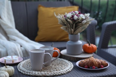 Photo of Rest on terrace with rattan furniture. Drink, dessert and autumn decor on table