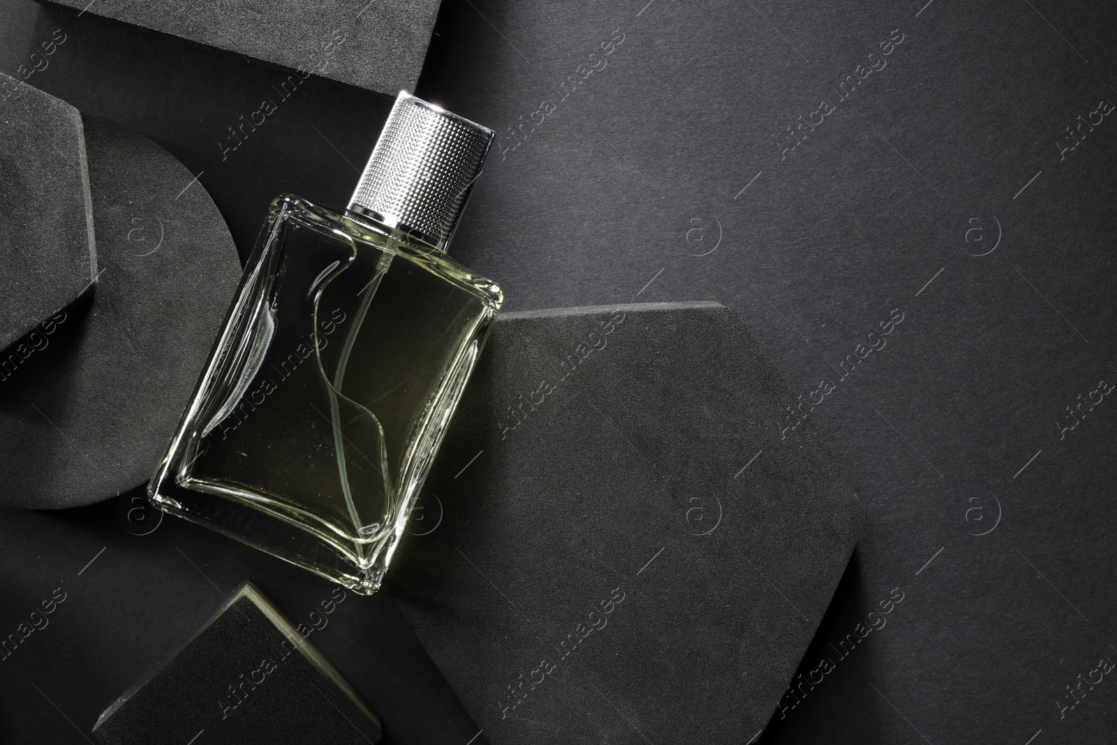 Photo of Stylish presentation of luxury men`s perfume in bottle on black background, top view. Space for text