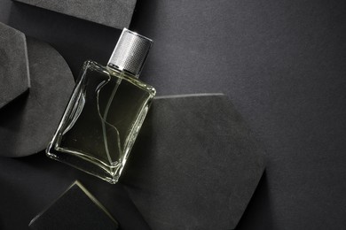 Stylish presentation of luxury men`s perfume in bottle on black background, top view. Space for text