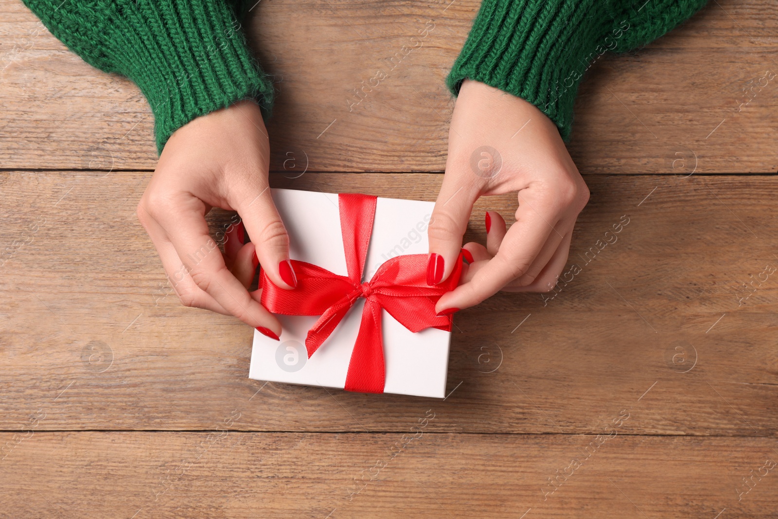 Photo of Christmas present. Woman with gift box at wooden table, top view